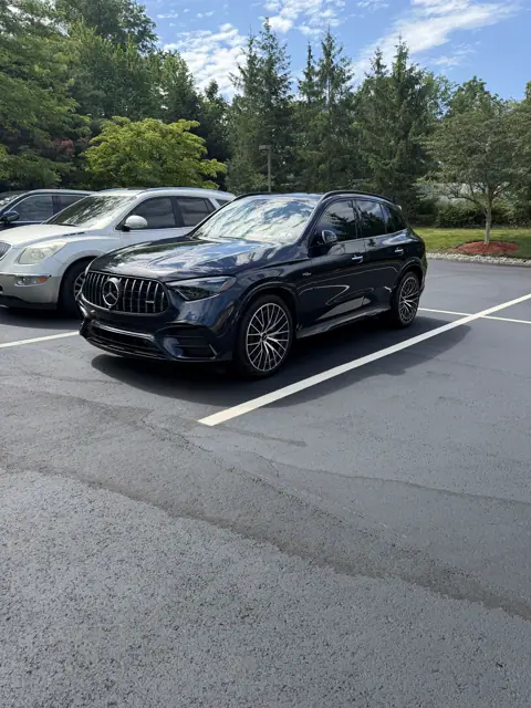 Dark SUV with reflective paint and multi-spoke wheels parked outdoors