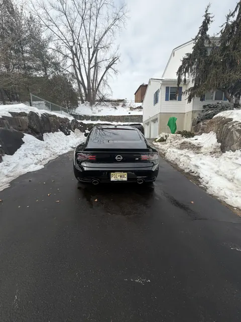 Dark sedan rear lights and trunk on a residential street