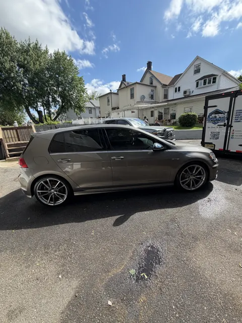 Side view of a dark sedan beside a house