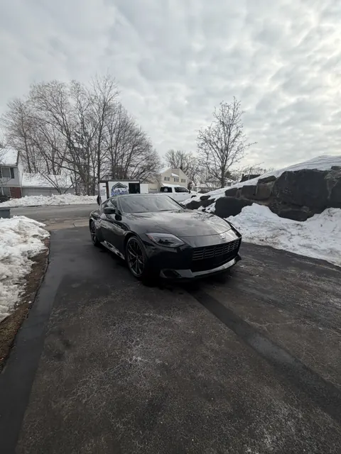 Dark sedan viewed from the front beside a snowy curb