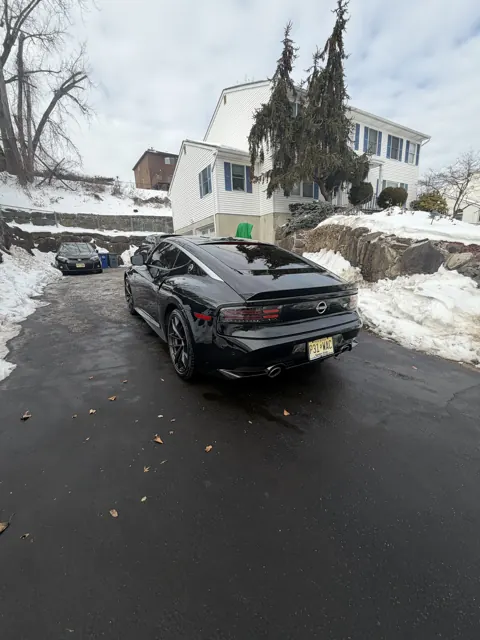 Dark sedan viewed diagonally on a snowy residential street