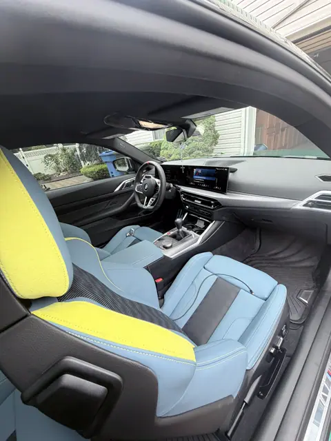 Front cabin with blue and yellow seats, black dashboard, and clean floor mats