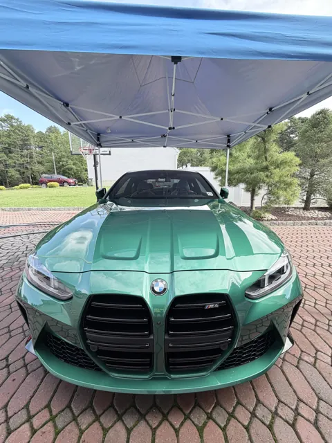 Front view of a green coupe beneath a blue canopy