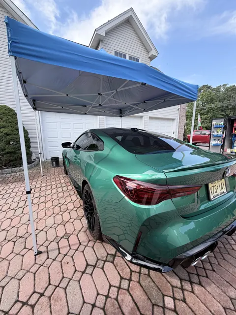 Rear view of a green coupe under a blue canopy