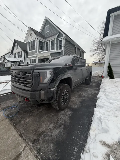 Dark pickup truck beside a house in winter