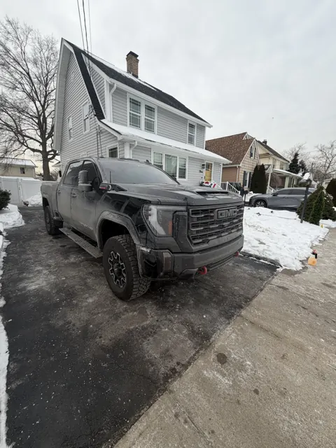 Dark pickup truck viewed from the front in a snowy driveway