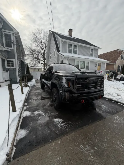 Dark pickup truck parked beside a house