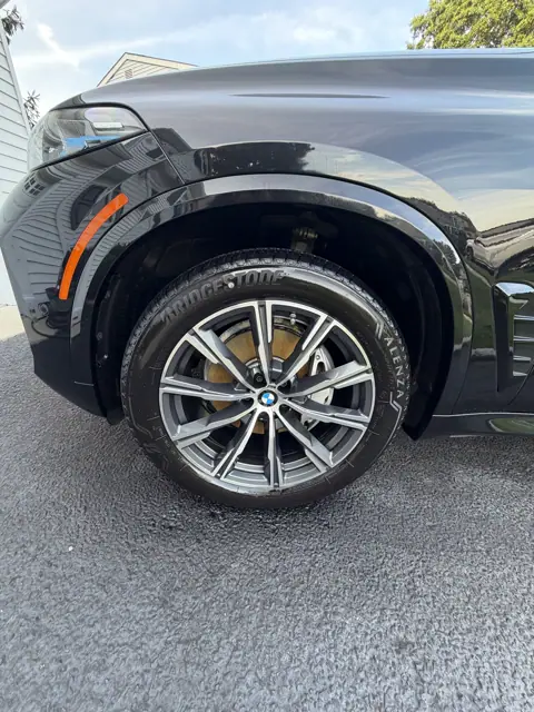 Close-up of a multi-spoke alloy wheel and tire beneath a glossy dark fender