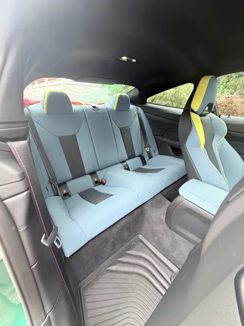Rear seats upholstered in light blue with yellow headrest accents and a clean floor mat