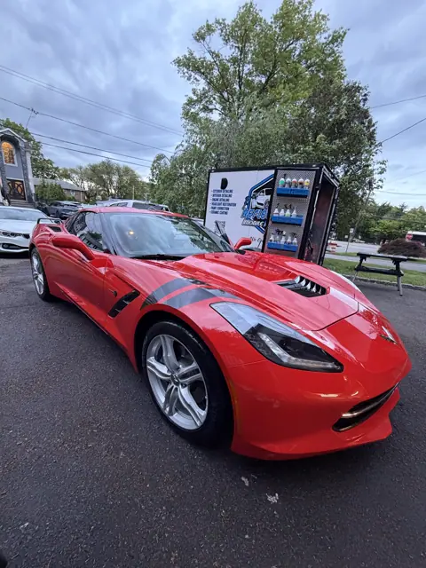 Glossy red sports car parked beside the Reflections detailing trailer