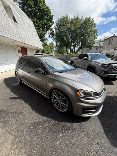 Silver hatchback parked in a driveway with bright reflections on its hood