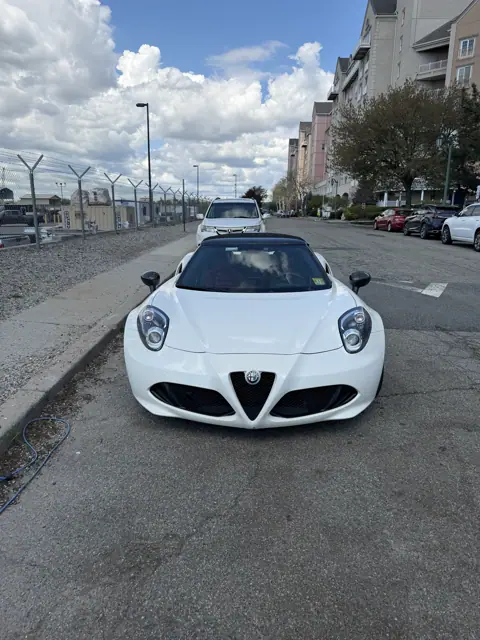 White sports car with distinctive triangular front grille parked on a city street