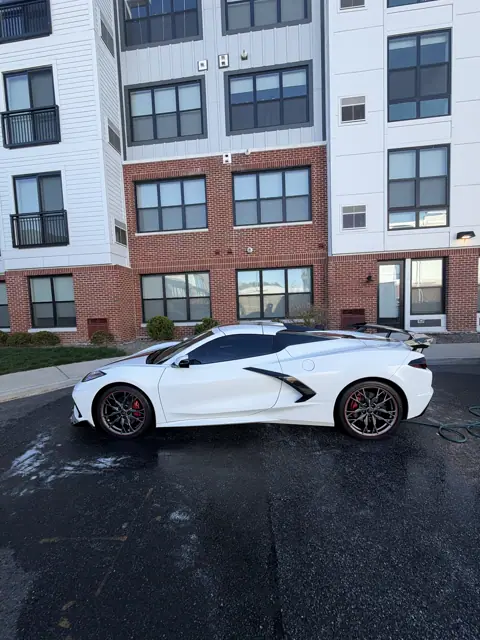 White sports car shown in profile with dark roof and red brake calipers