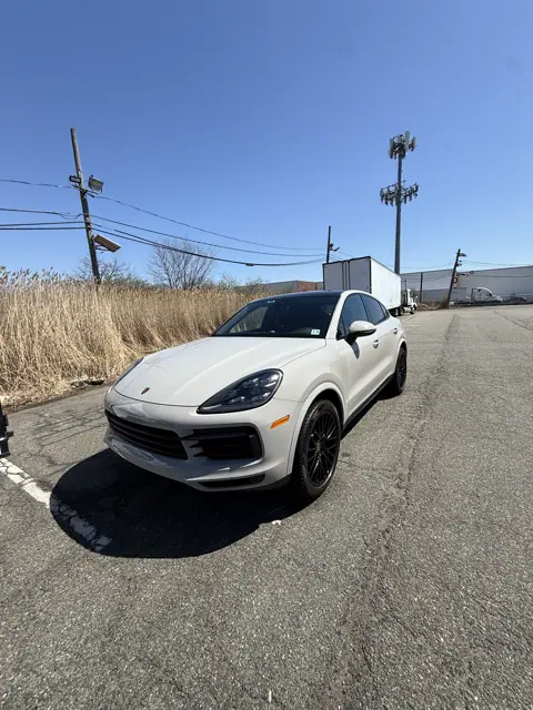 White SUV with dark wheels parked outdoors on a sunny day